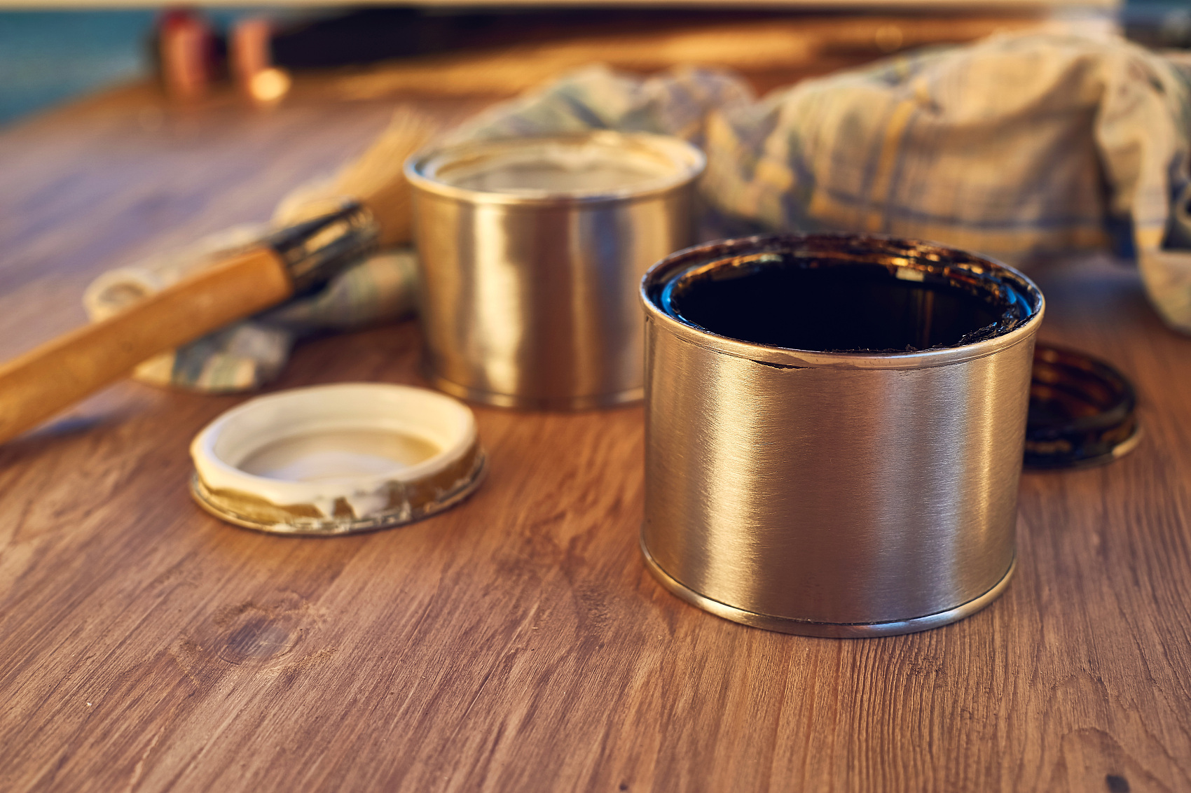 Close up on black and white paint bucket with brush and dirty rag on wooden background