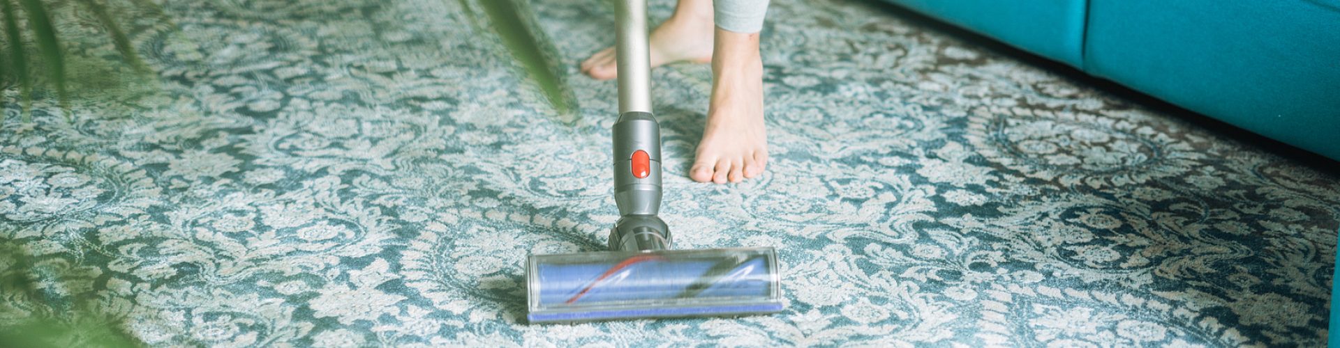 Close up photo of young woman using vacuum cleaner cleaning carpet floor at home