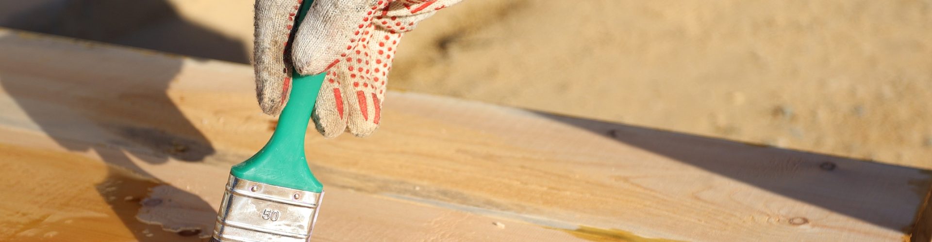 A master in gloves to paint wooden boards with a brush with varnish