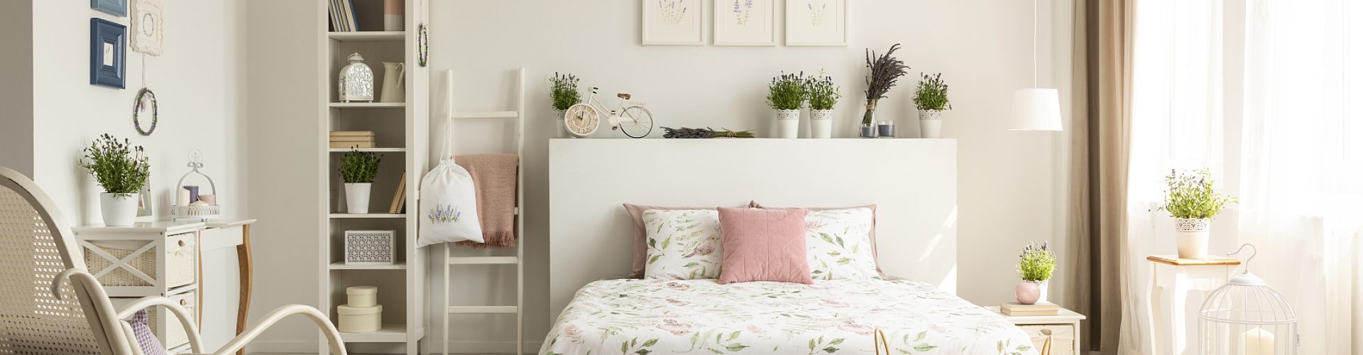 White bedroom interior with dirty pink carpet, rocking chair, window with drapes and king-size bed in the real photo