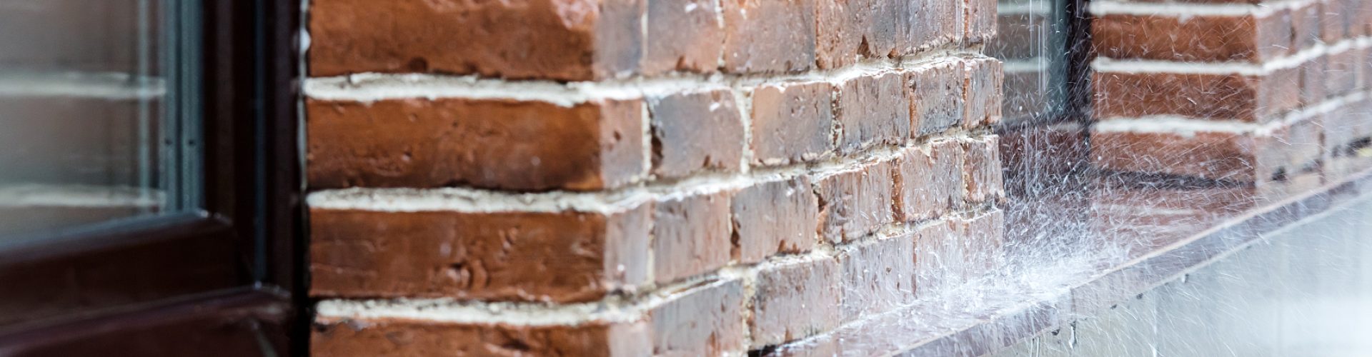 heavy rain pouring on pavement on red brick wall background