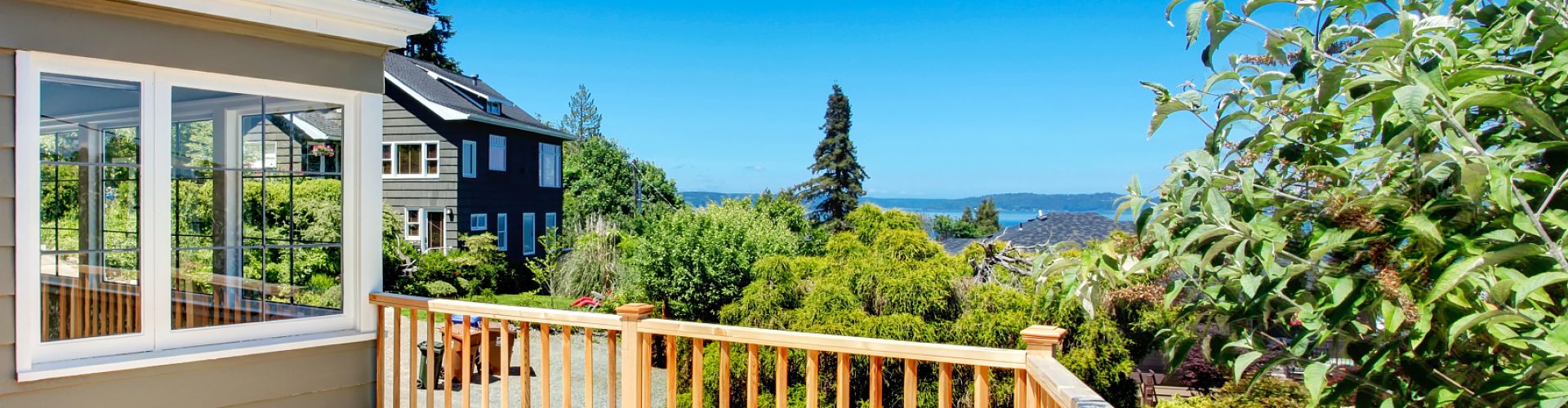 Wooden walkout deck with railings. Deck overlooking driveway and neighborhood