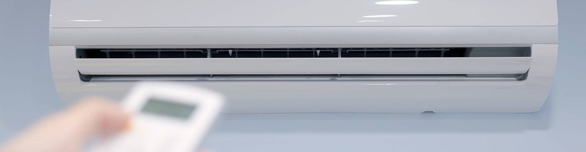 Energy Efficient concept - Close up shot of turning on split type air conditioner on the blue wall