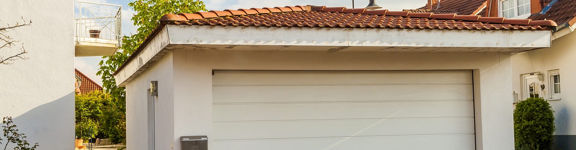 Detached white garage with orange brick tile roof