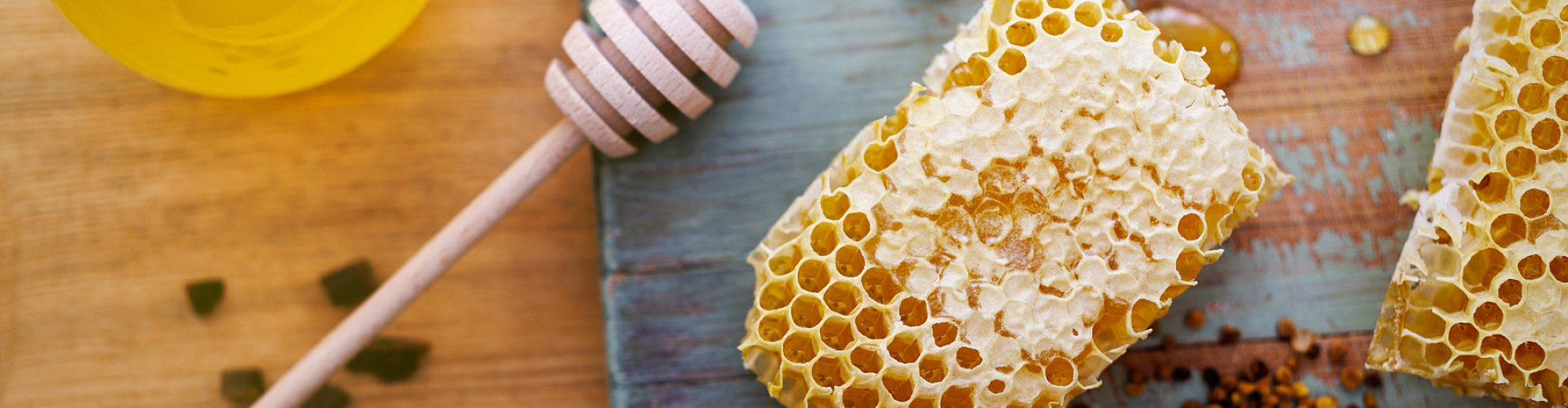 Honey background. Sweet honey in a glass jar, honeycombs, propolis and pollen on the table.