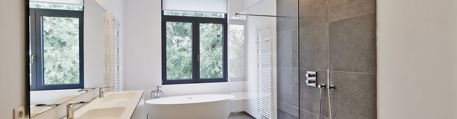 Bathtub in corian, Faucet and shower in tiled bathroom with windows towards garden